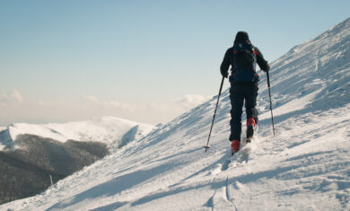 Ski touring man in the mountains. Winter activity on fresh air. Sunny day with white snow and blue sky.