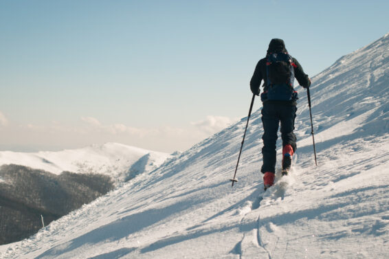 Ski touring man in the mountains. Winter activity on fresh air. Sunny day with white snow and blue sky.