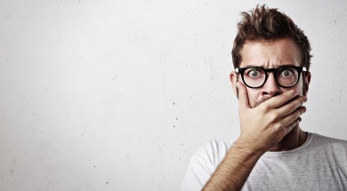 Portrait of a young man covering his mouth with hand