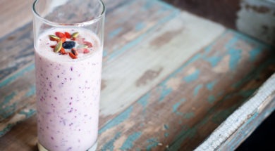 Healthy smoothie made from blended pineapple and kefir yogurt topped with pumpkin seeds, goji berries and a blueberry. Served on a wooden tray, this is a healthy, nutritious breakfast